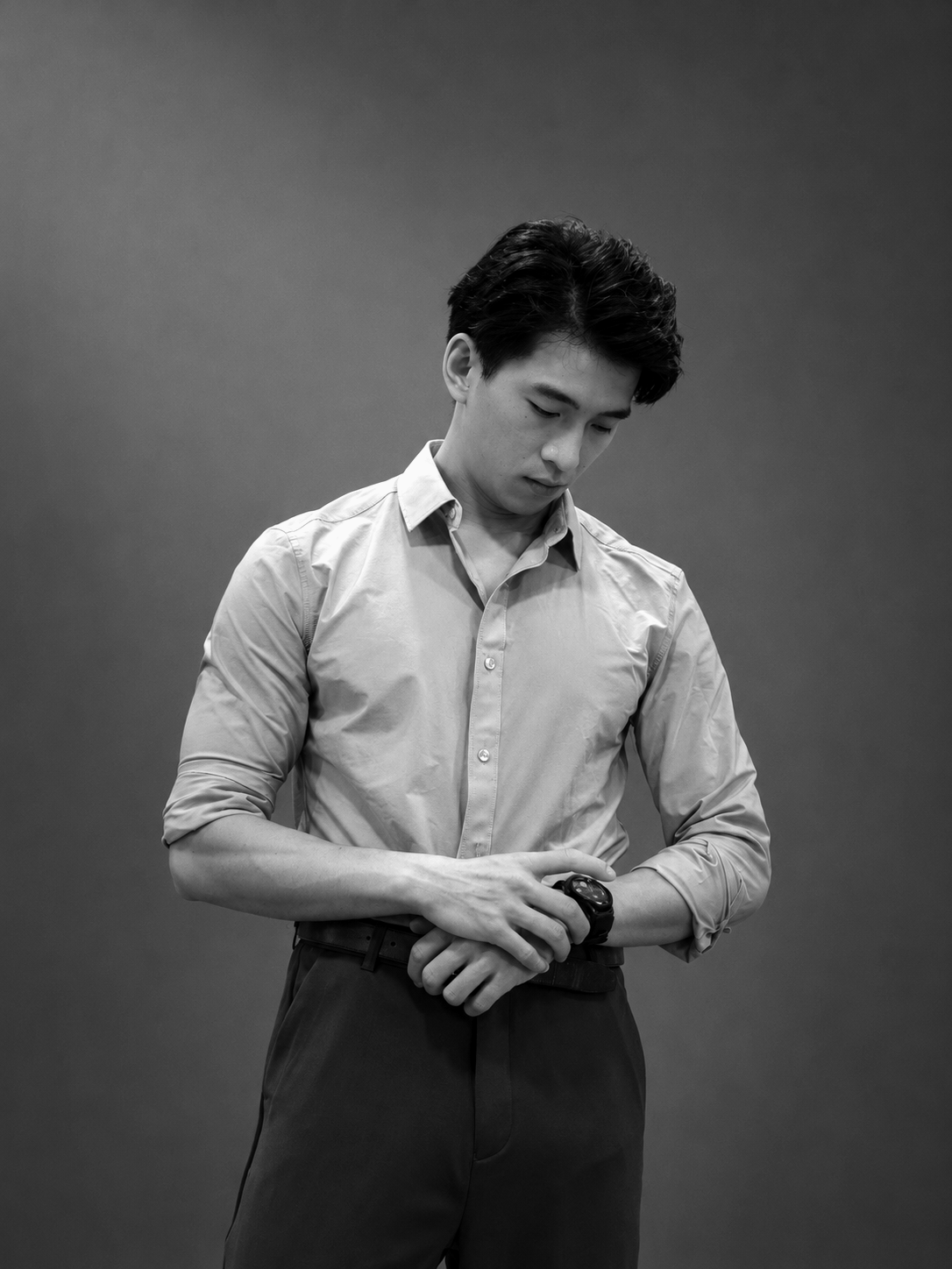 Black-and-white portrait of Terrence Leung adjusting his watch in an open-collar shirt.