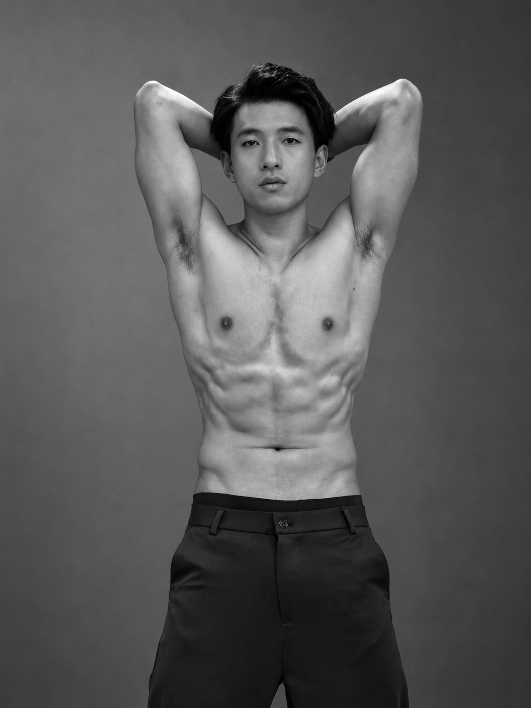 Black-and-white studio portrait of Terrence Leung with arms raised, a dramatic study of gesture and form.